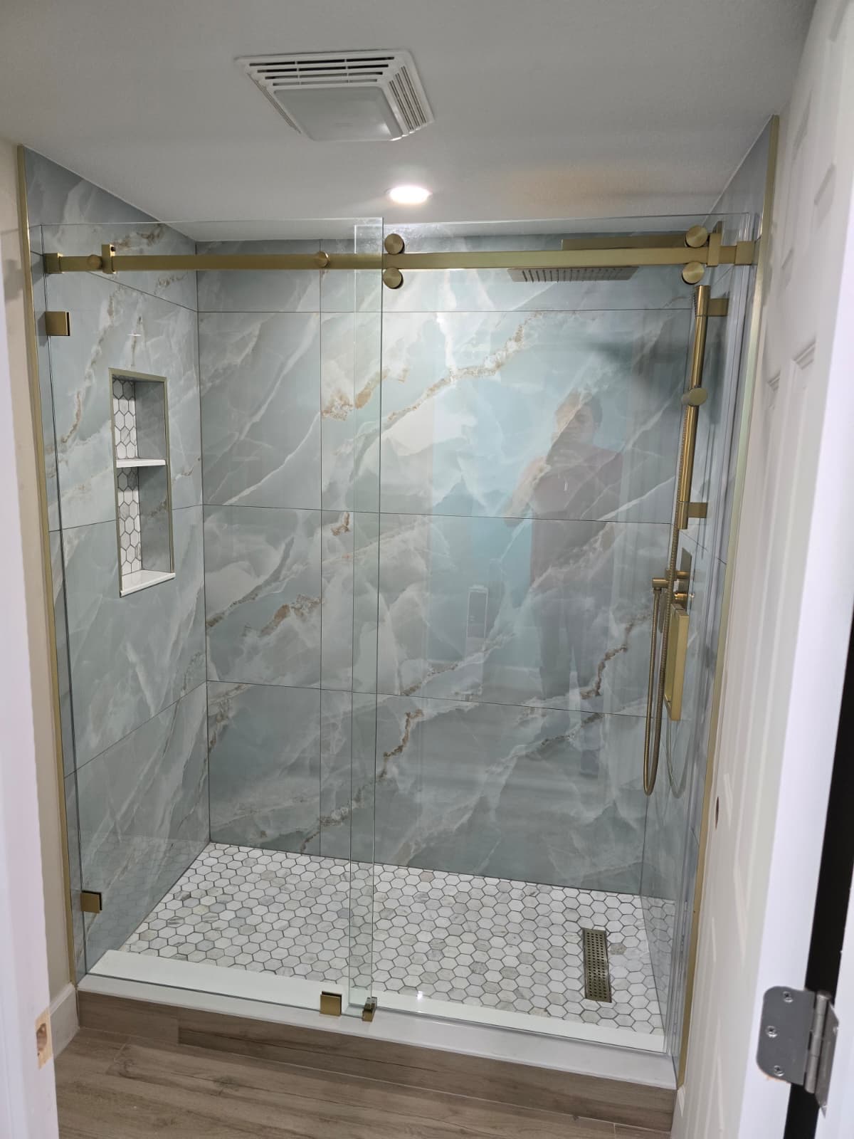 Marble shower remodel with brushed gold hardware