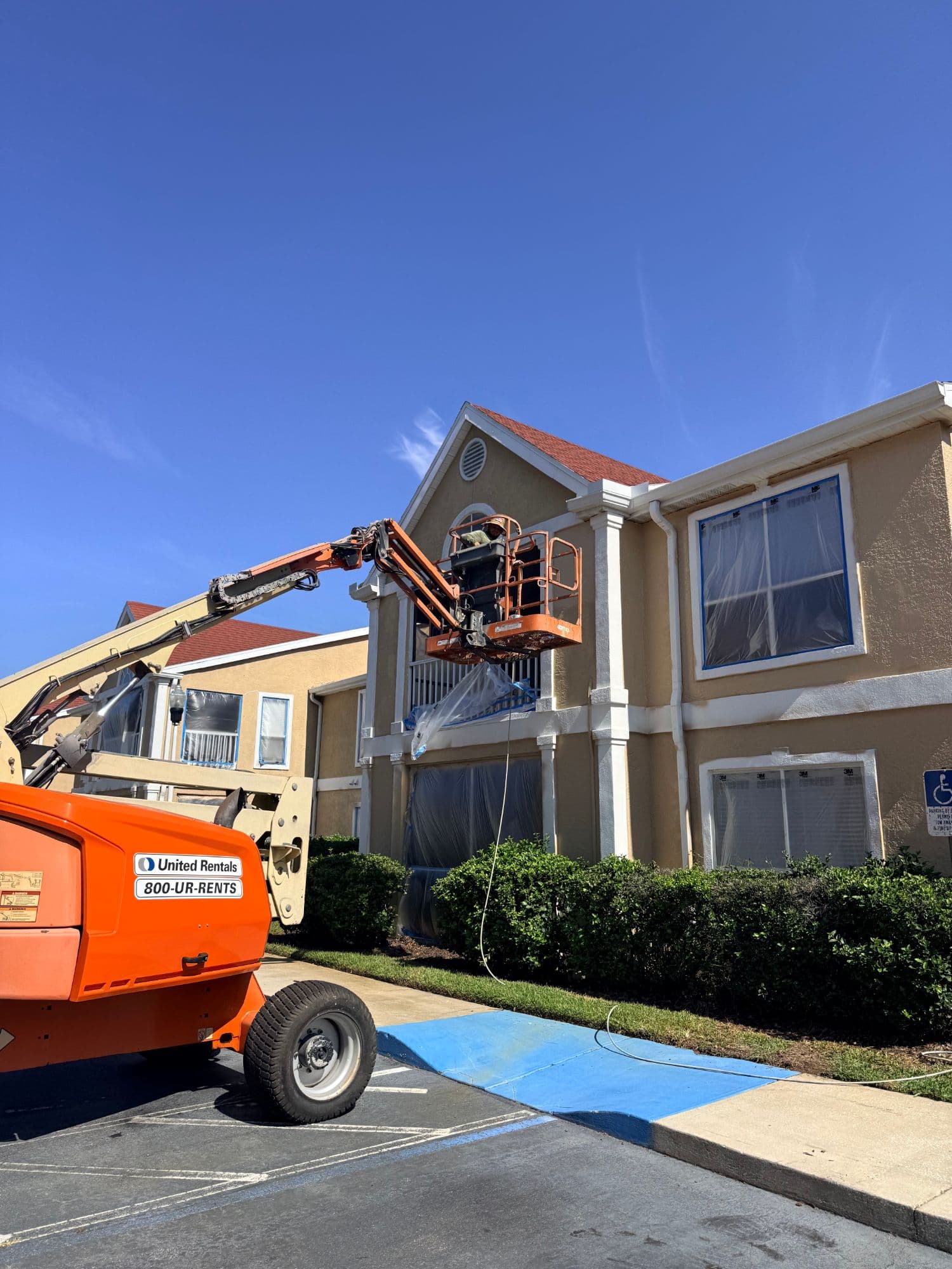 ROOSO crew restoring the exterior of a multifamily building on a boom lift